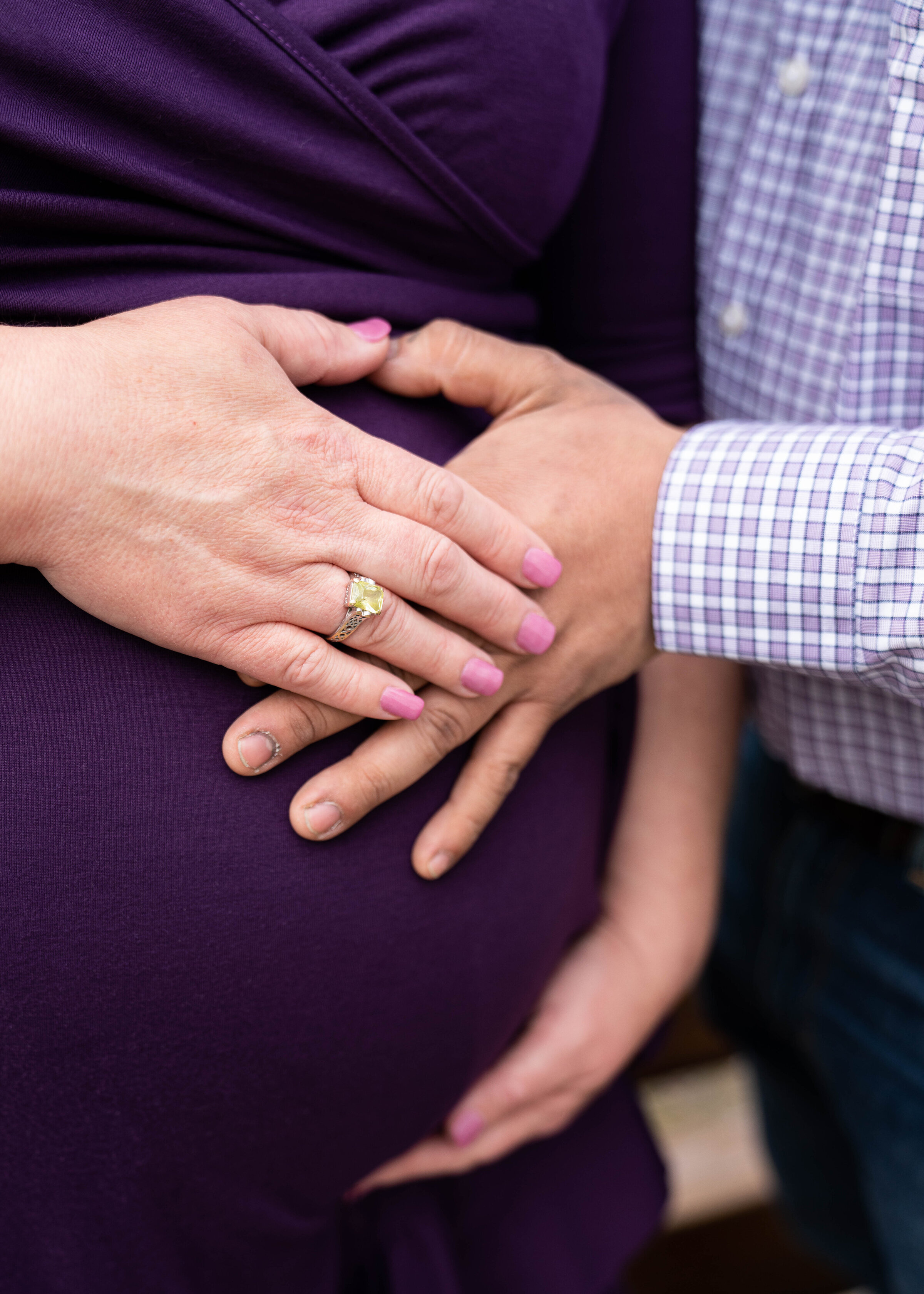 Couples places their hands on the woman's baby belly