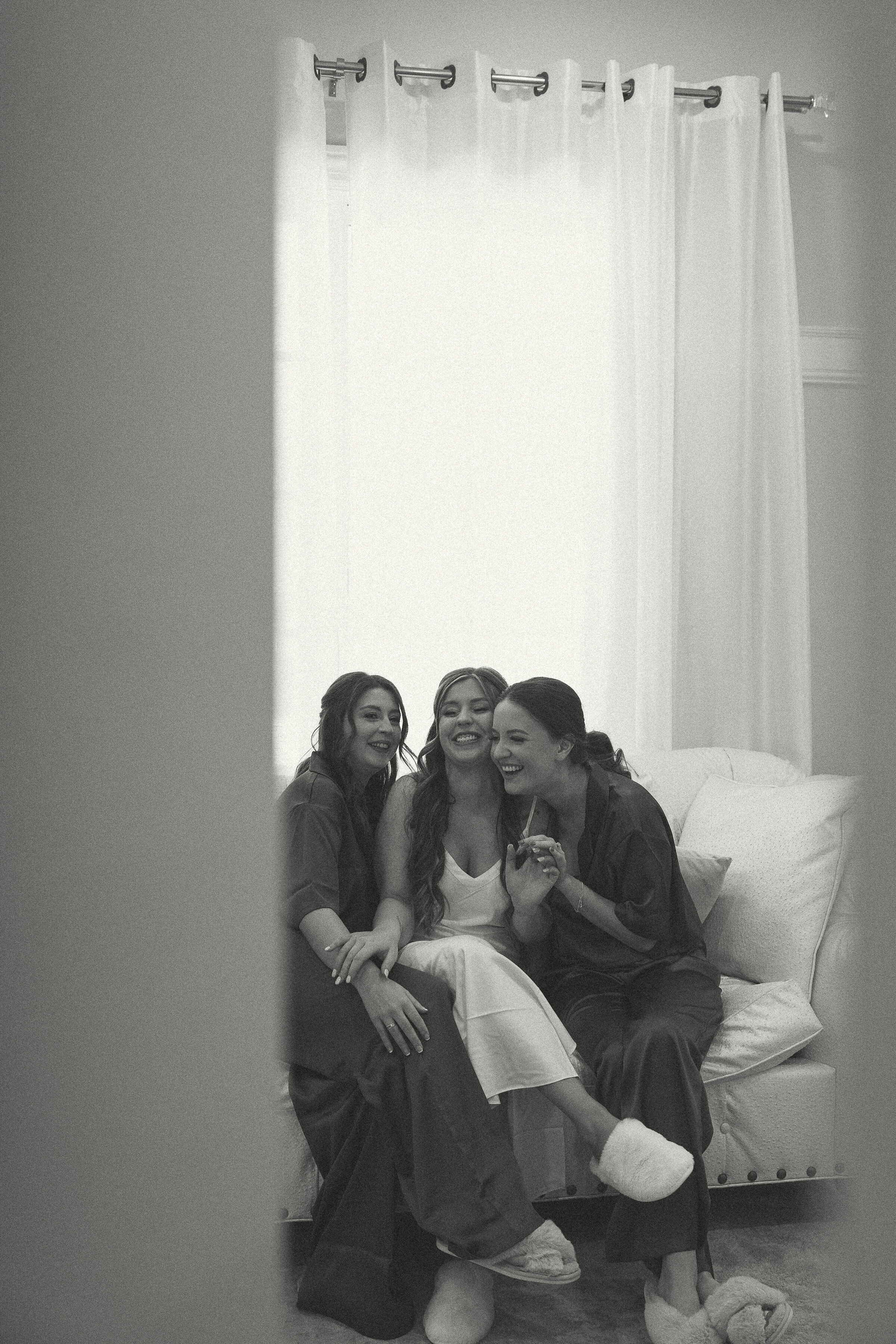 Bride and bridesmaids laughing together, candid moment during wedding preparations.