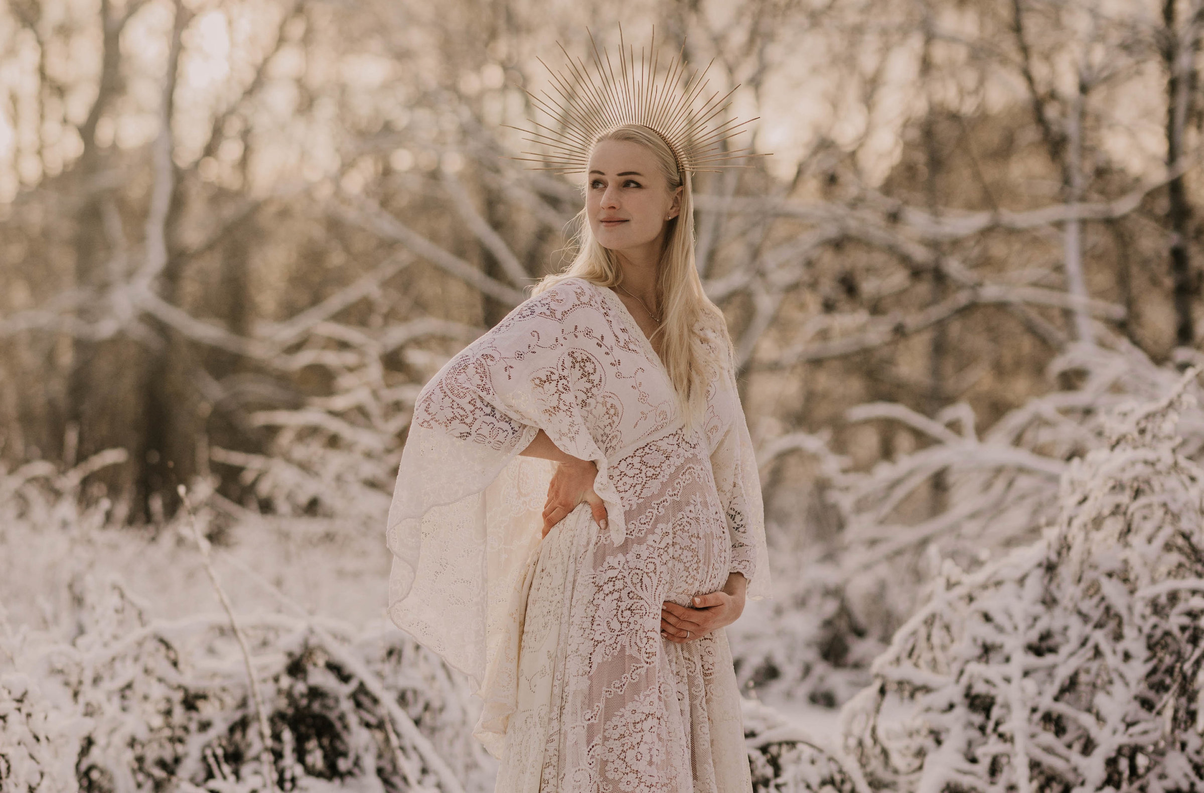 Gravidfotografering i snön med bohemisk spetsklänning och krona