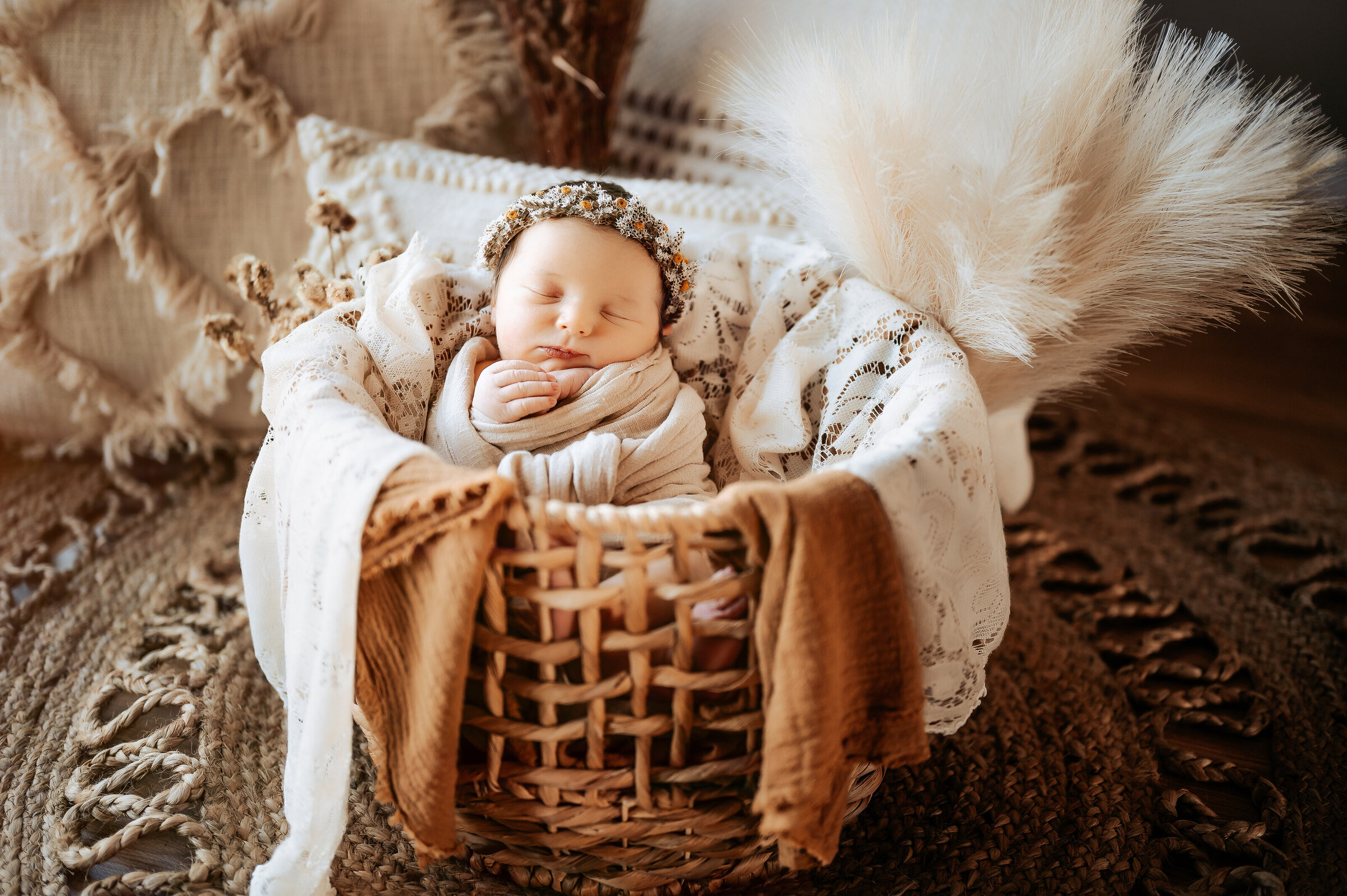 Baby sleeps in wooden crate swaddled with linen and wearing dried wheat headband