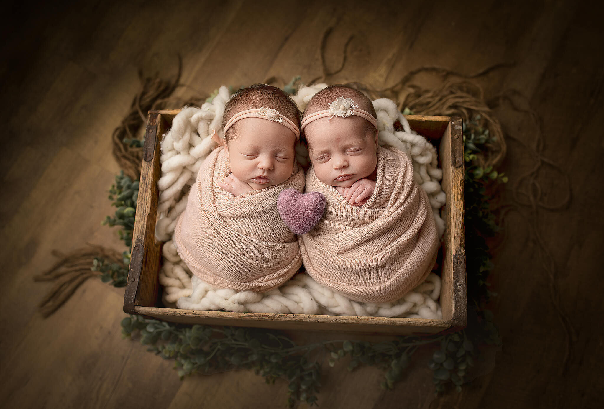 Twin girls  wrapped and placed a box next to each other with a little stuffed heart in between them.