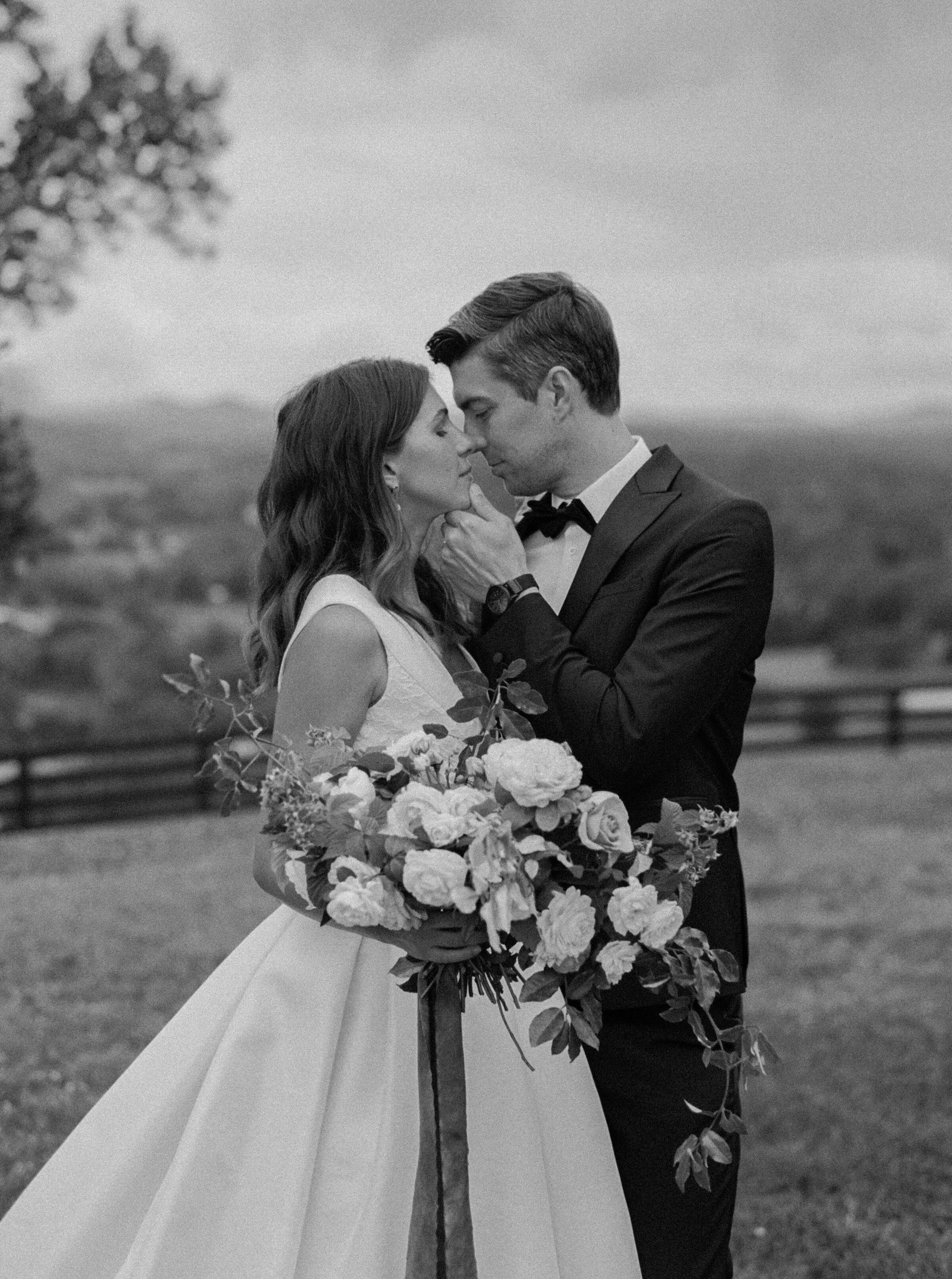 Groom in black tux holds bride close and pulls her in for a kiss after their wedding at Trinity View Farm in Nashville Tennessee photographed by Nashville wedding photographer Magnolia Tree Photo Company