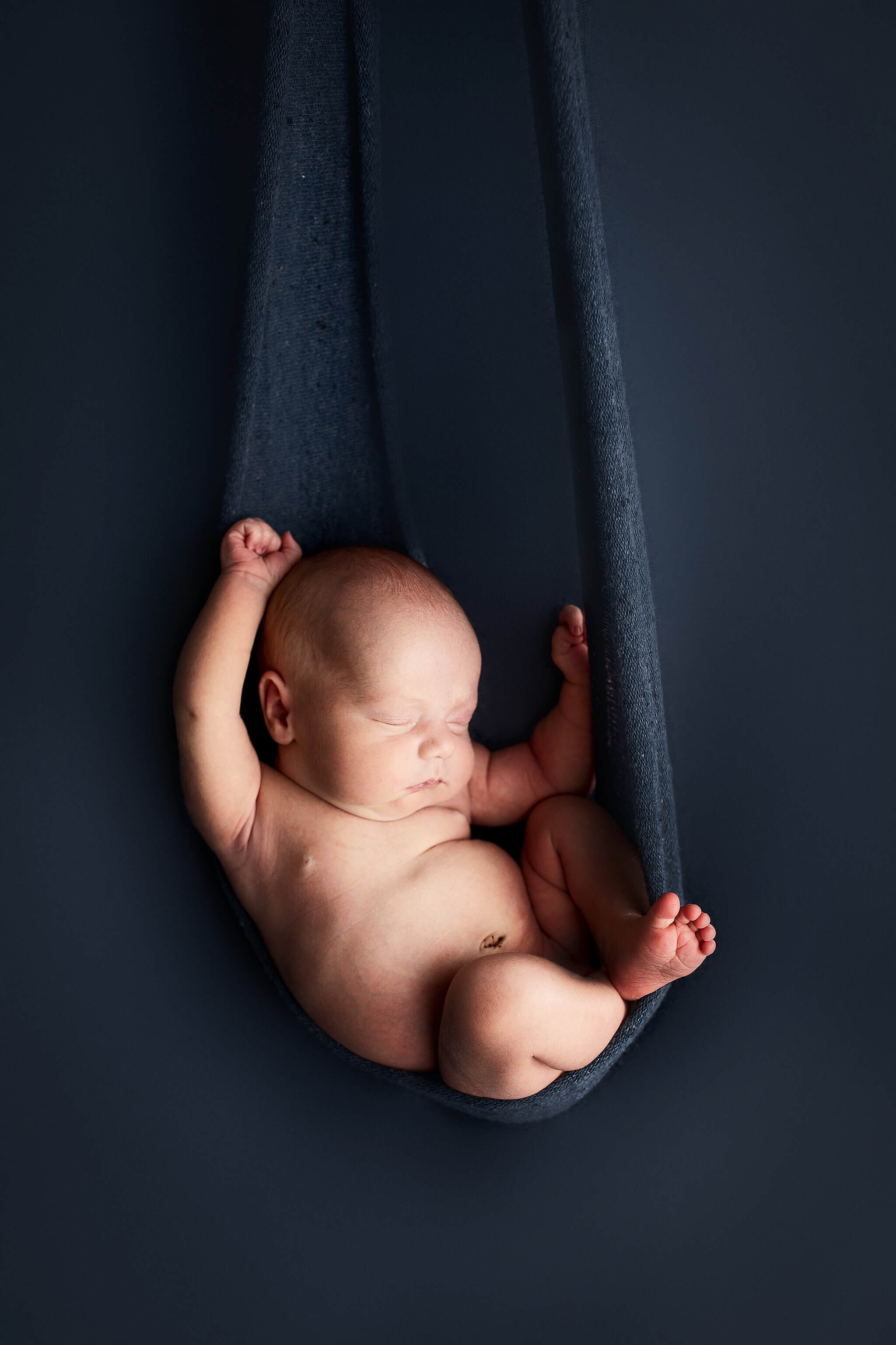 Newborn boy in navy blue , looks to be hanging wrap