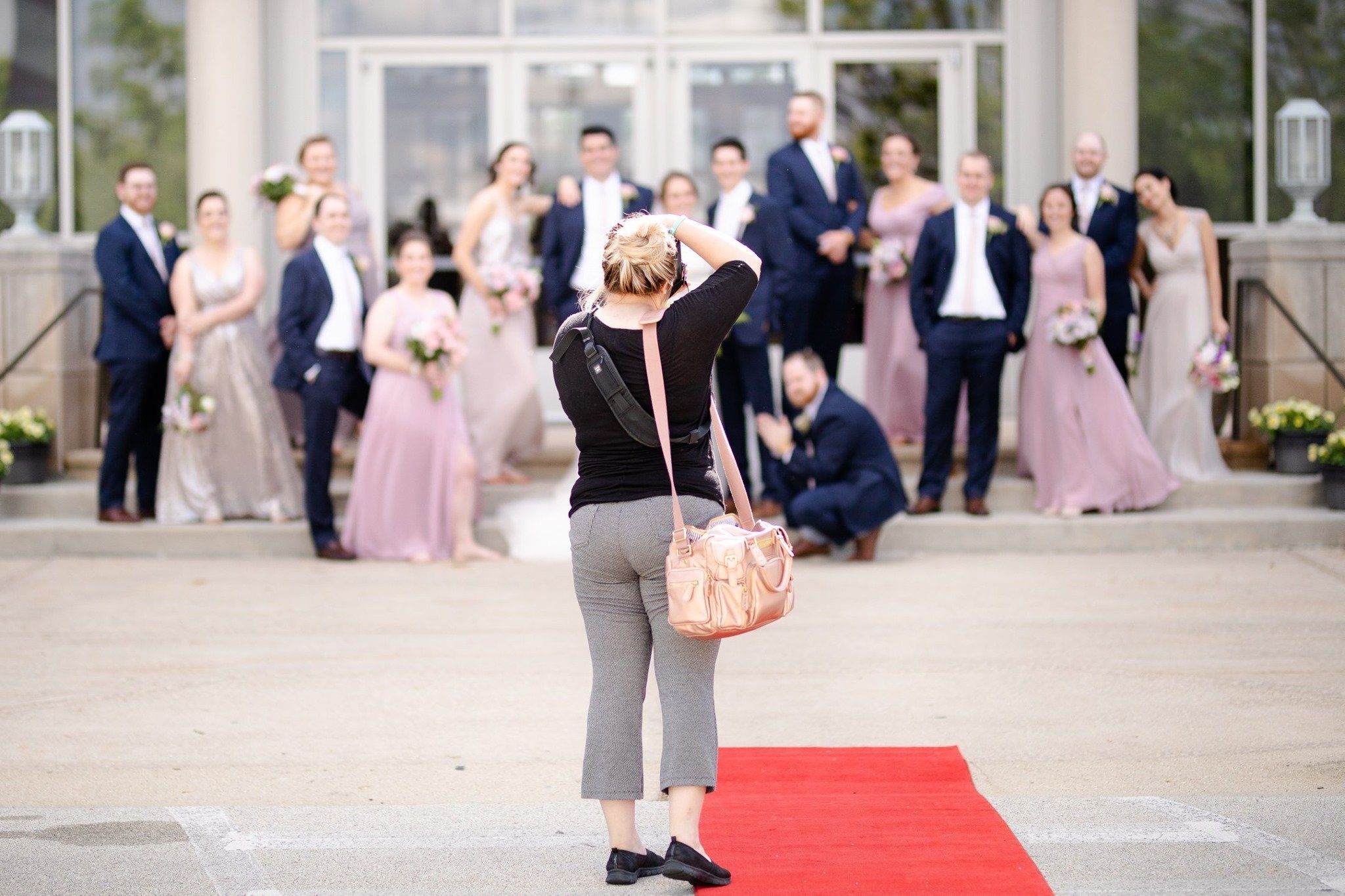 A view from the back of a woman taking a photo of a wedding party