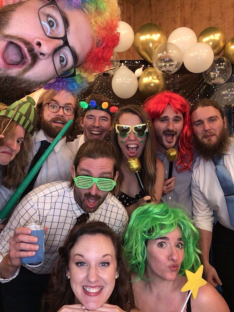 Large group photo of a lot of wedding guests making funny faces and wearing props