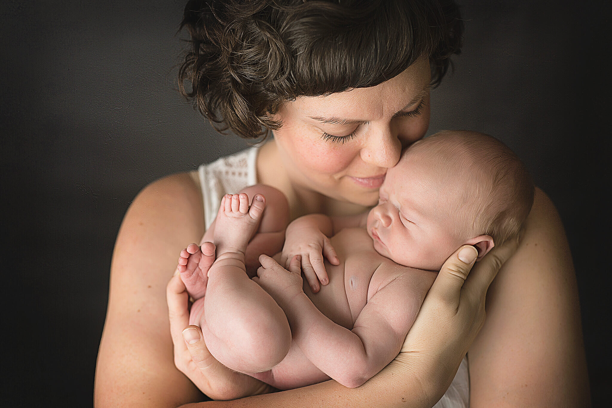 Newborn baby boy snuggled in mothers arms, in bucyrus ohio photography studio