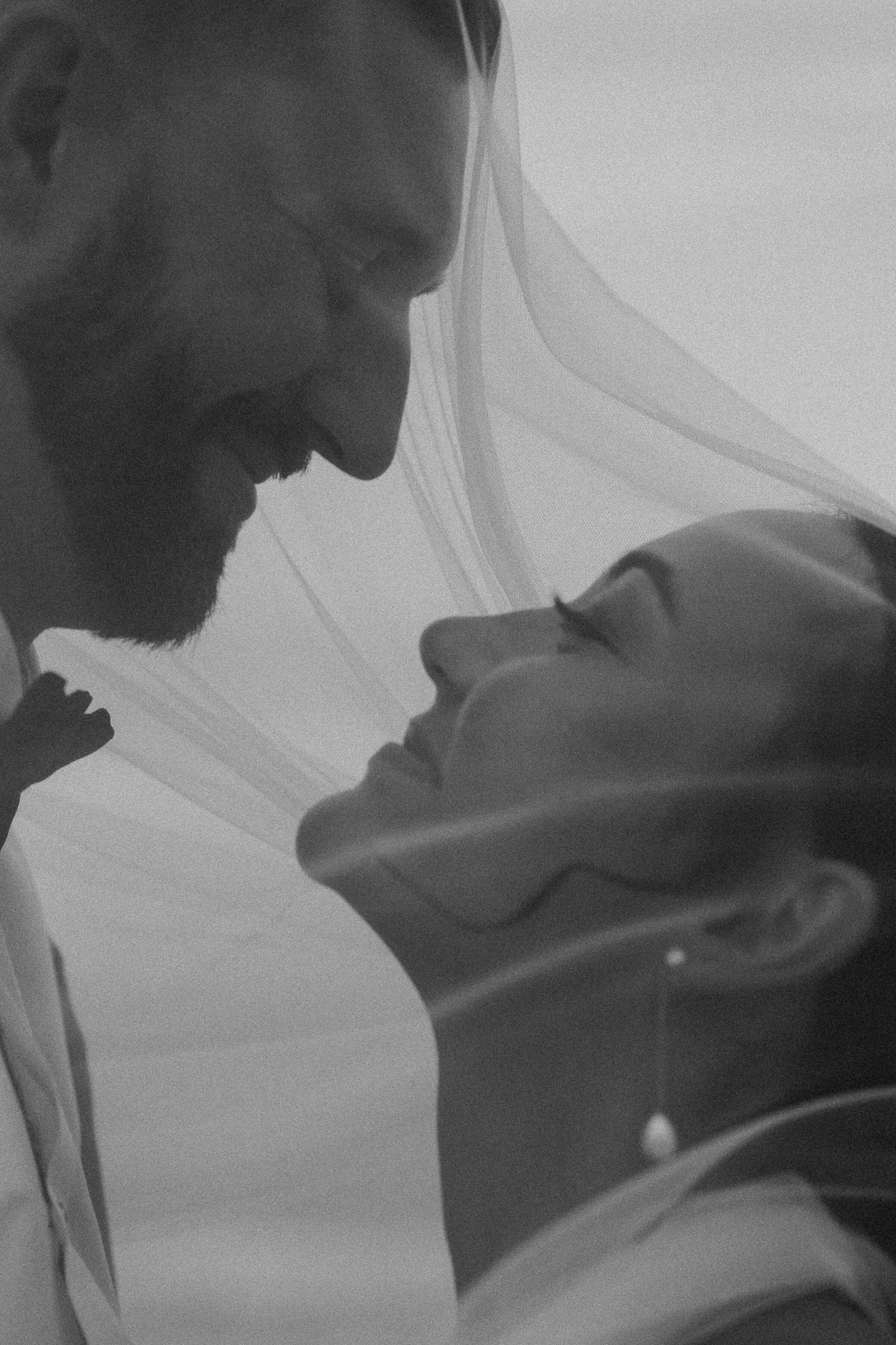 Intimate black and white photo of a couple under a veil.