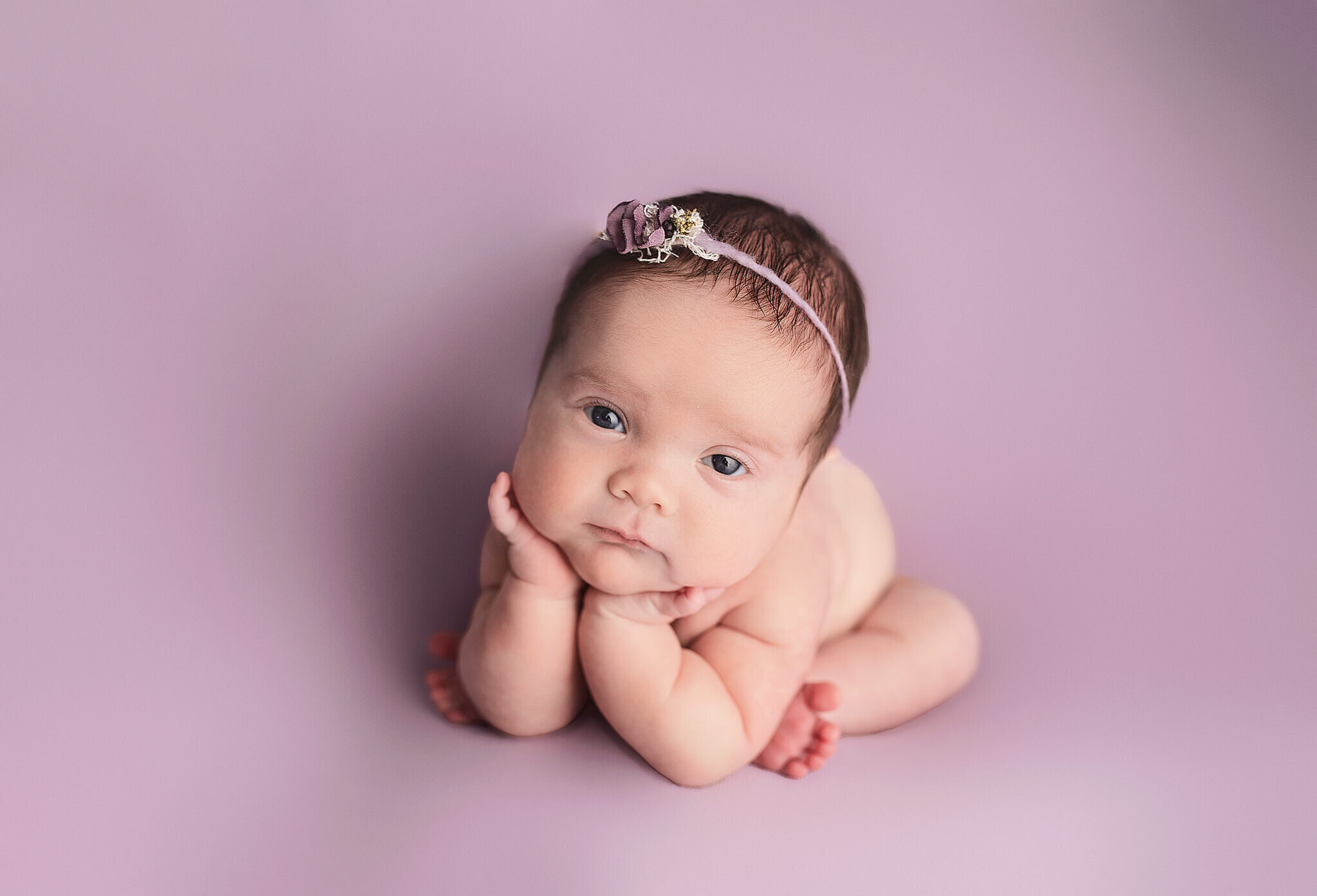 Newborn girl in froggy post while awake on pink background at bucyrus ohio photography studio