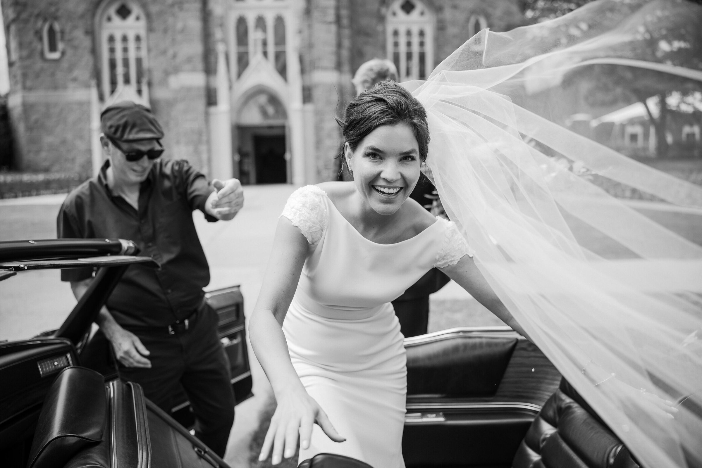 A candid moment of the bride getting into the vintage cabriolet with the veil flowing after her wedding ceremony at Cathedral Basilica of Sacred Heart in New Jersey.