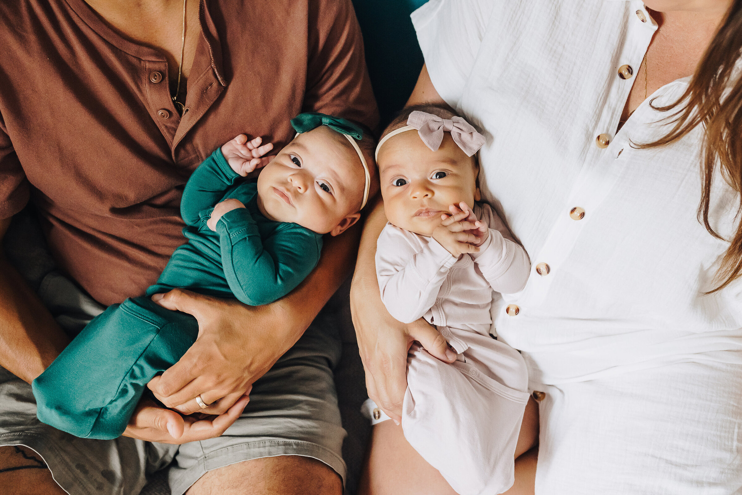 Twin girls are held by their parents during a lifestyle newborn session at home