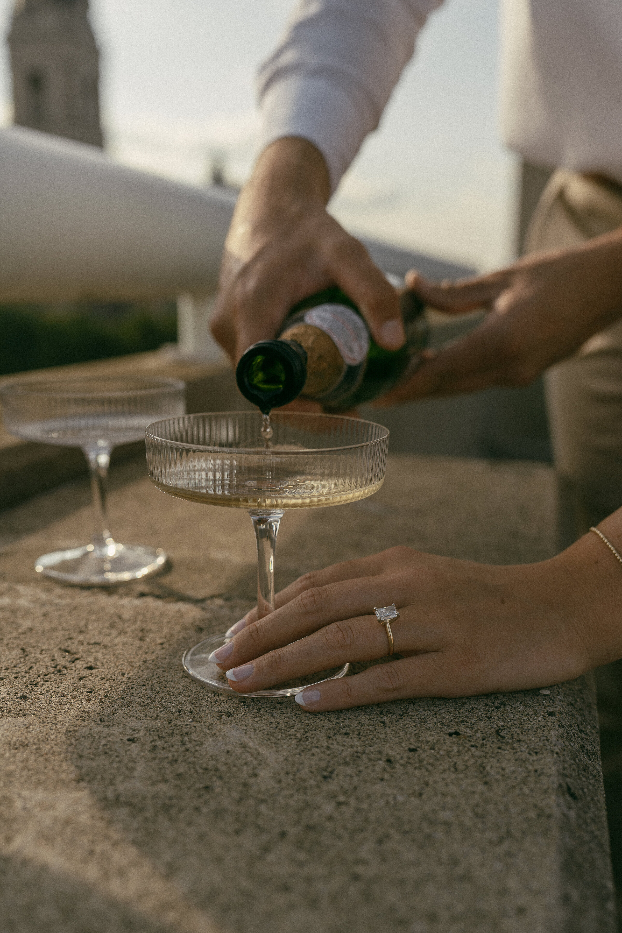 Close-up of a hand with an engagement ring while pouring champagne.