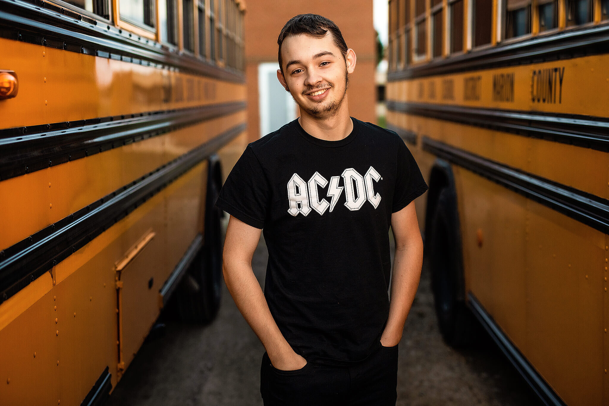 High school senior boy wearing acdc shirt standing between buses at school in marion ohio