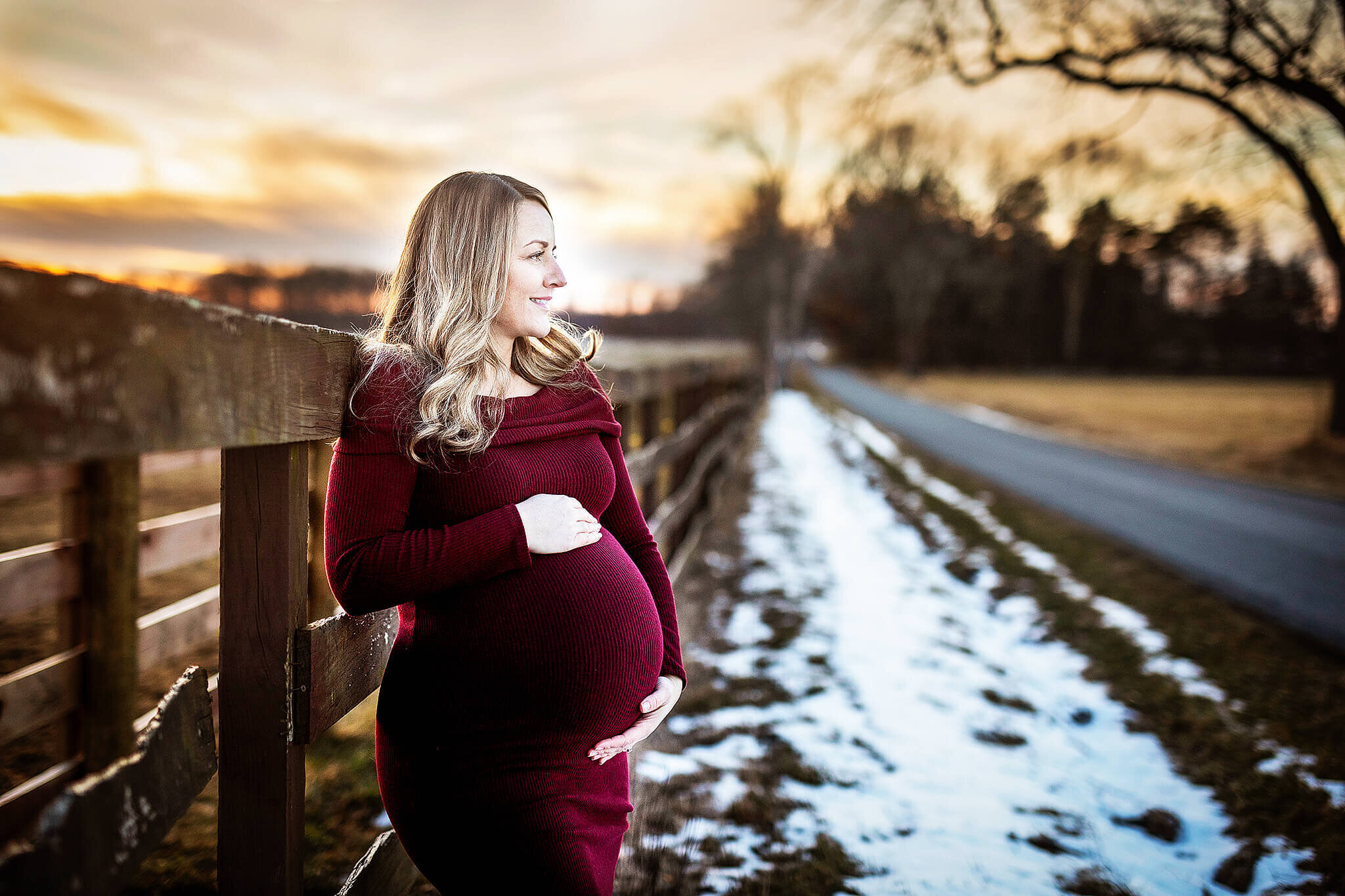 Pregnant  women in red dress standing along a fence line in winter in bucyrus ohio