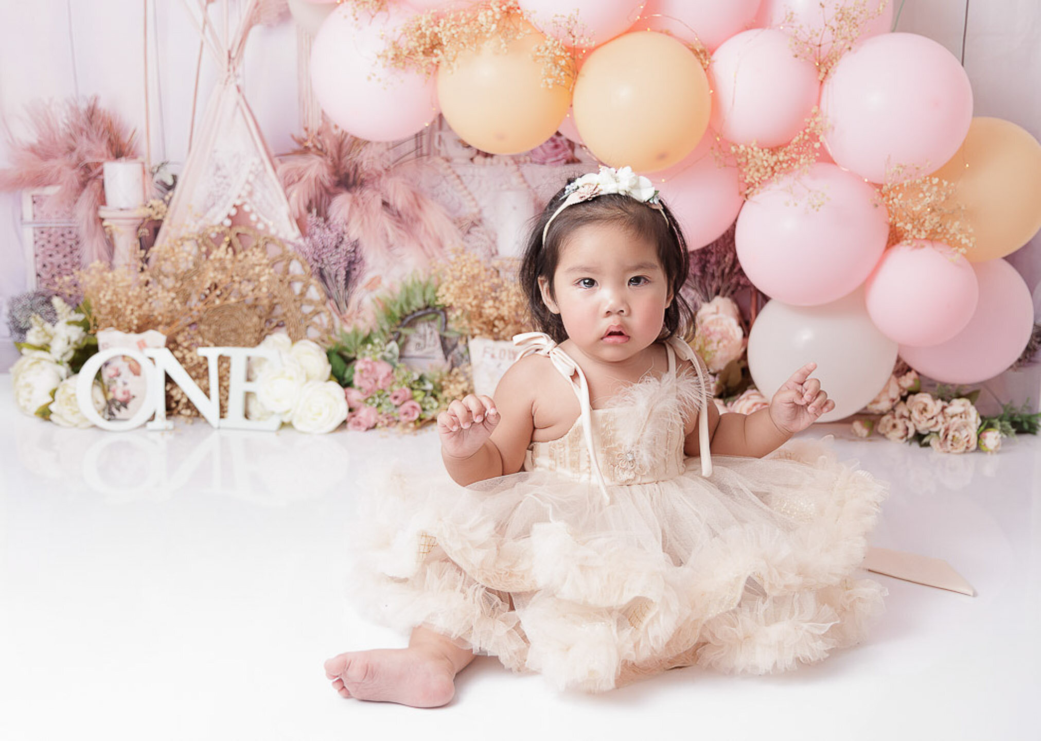 baby girl wearing  beige gown, pre-birthday photoshoot