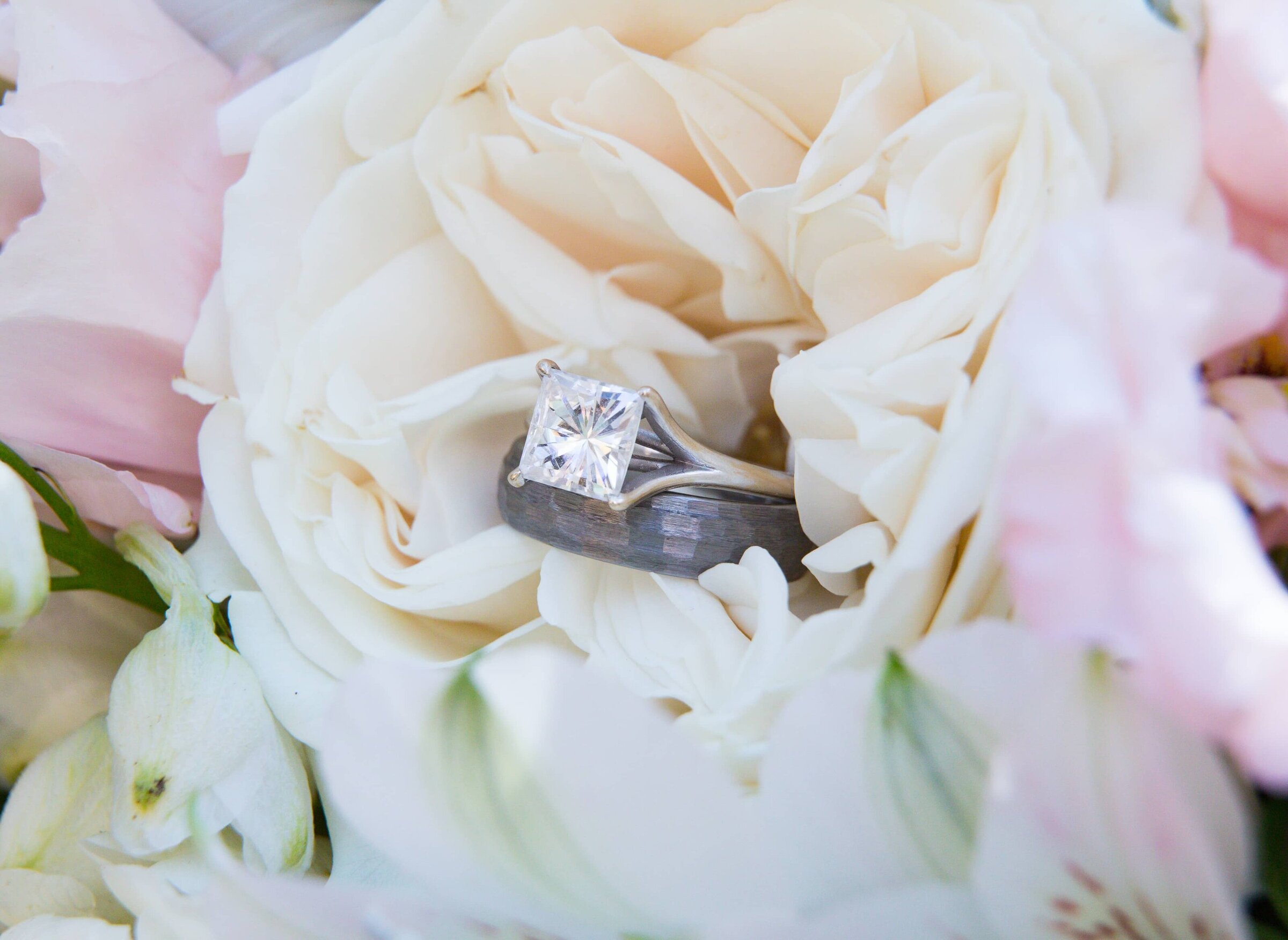 square diamond engagement ring against a white rose. Top Raleigh wedding photographers.