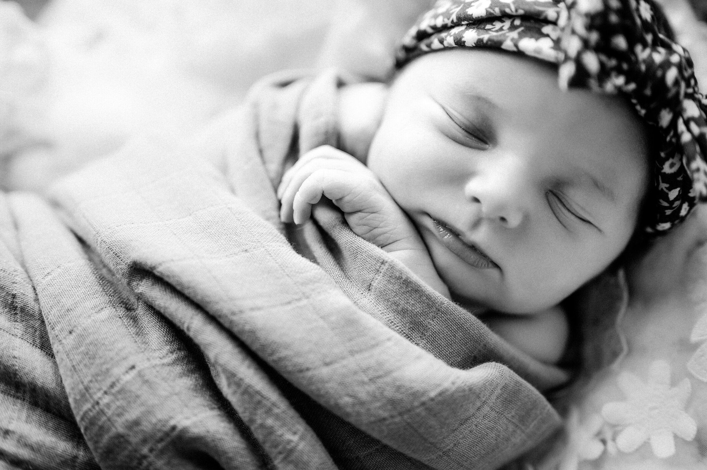 Baby sleeps in swaddle in floral headband