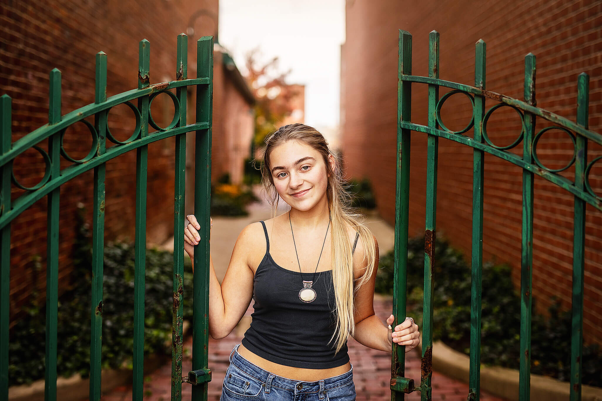 High school senior from marion Ohio wearing black tank and jeans holding onto green fence downtown mansfield ohio