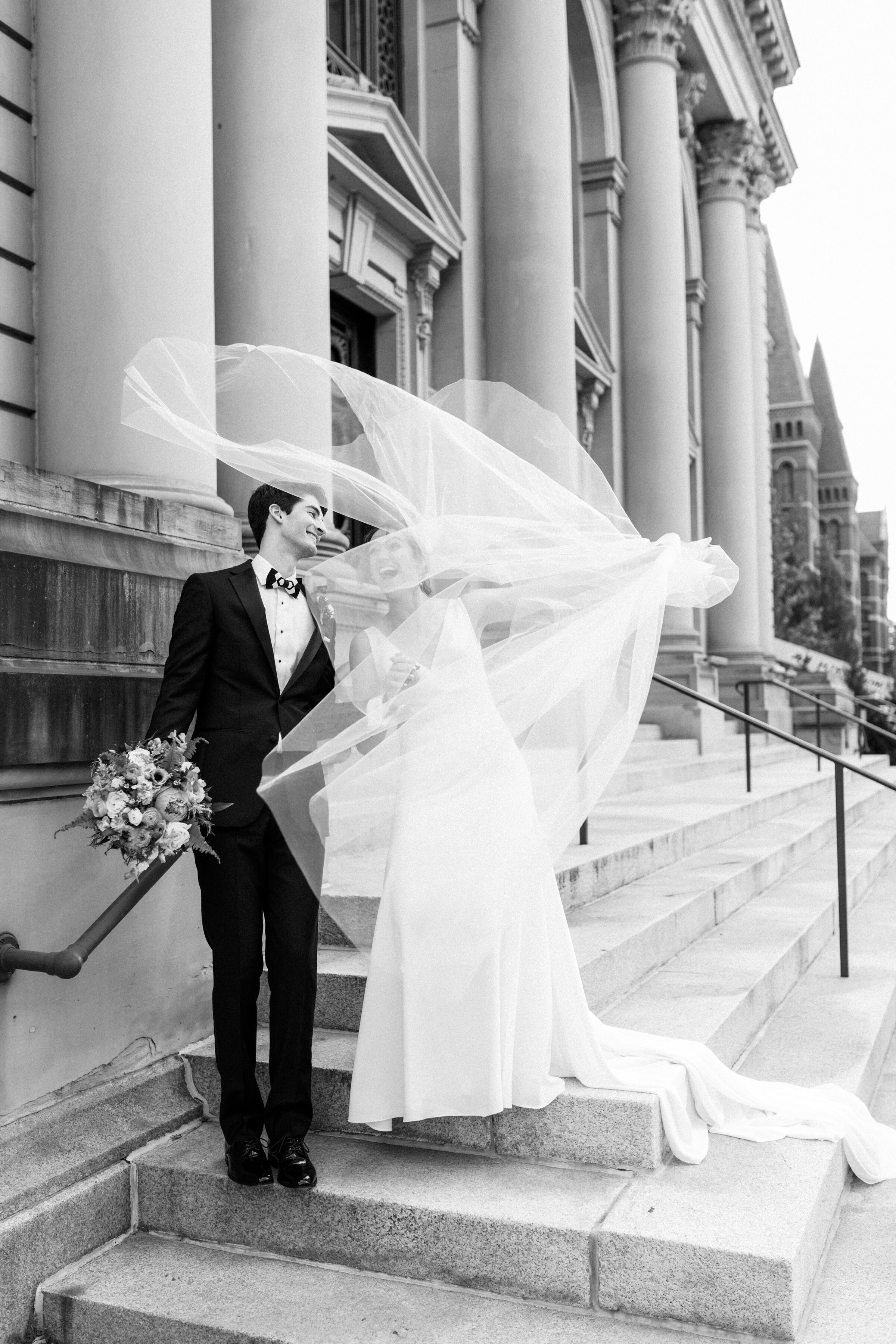 A bride's veil blows in the wind walking down Memorial Hall stairs downtown Cincinnati.