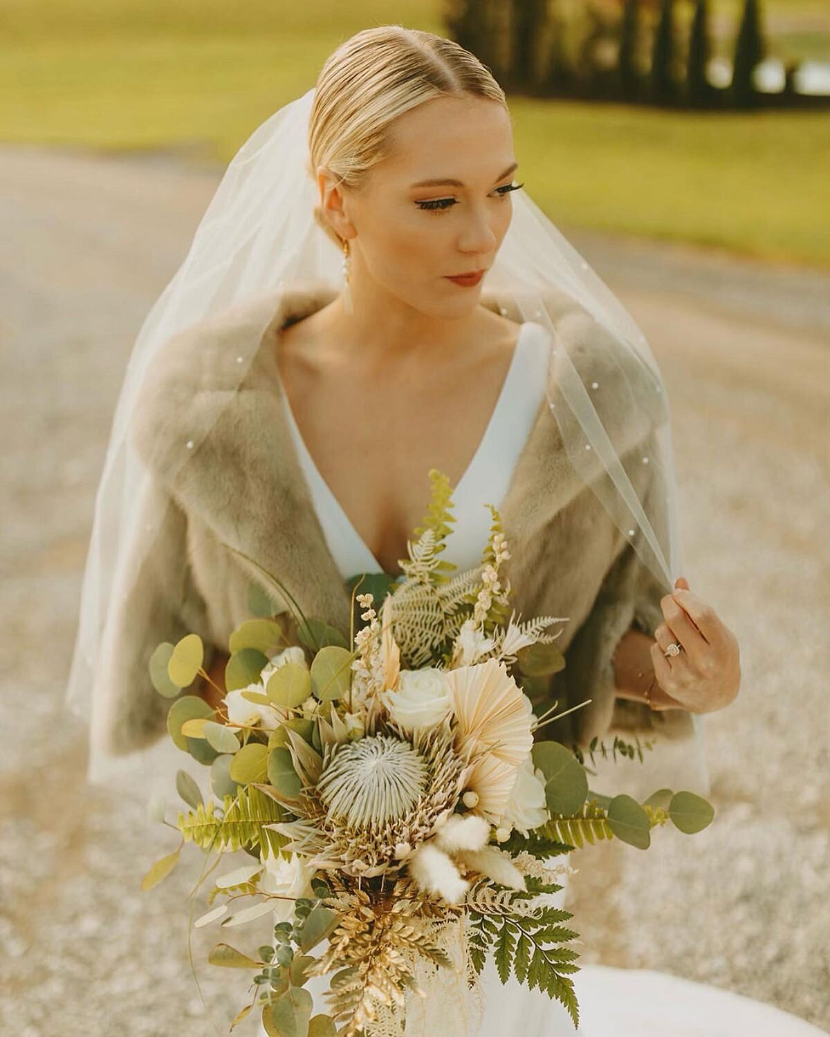 Boho bride holding bouquet with protea