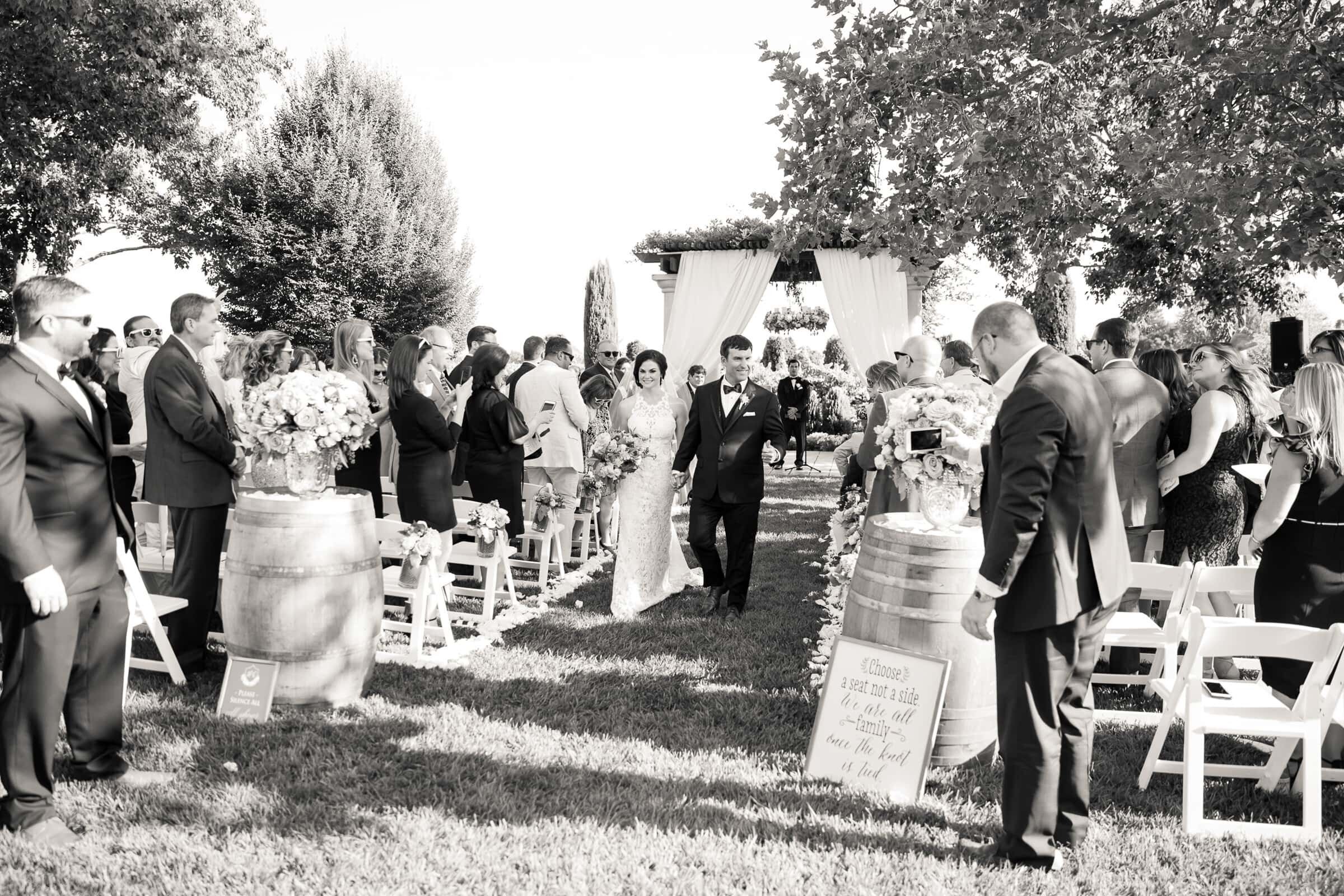 wedding recessional. newlyweds walking up the aisle after tying the knot at their outdoor wedding venue in raleigh nc,
