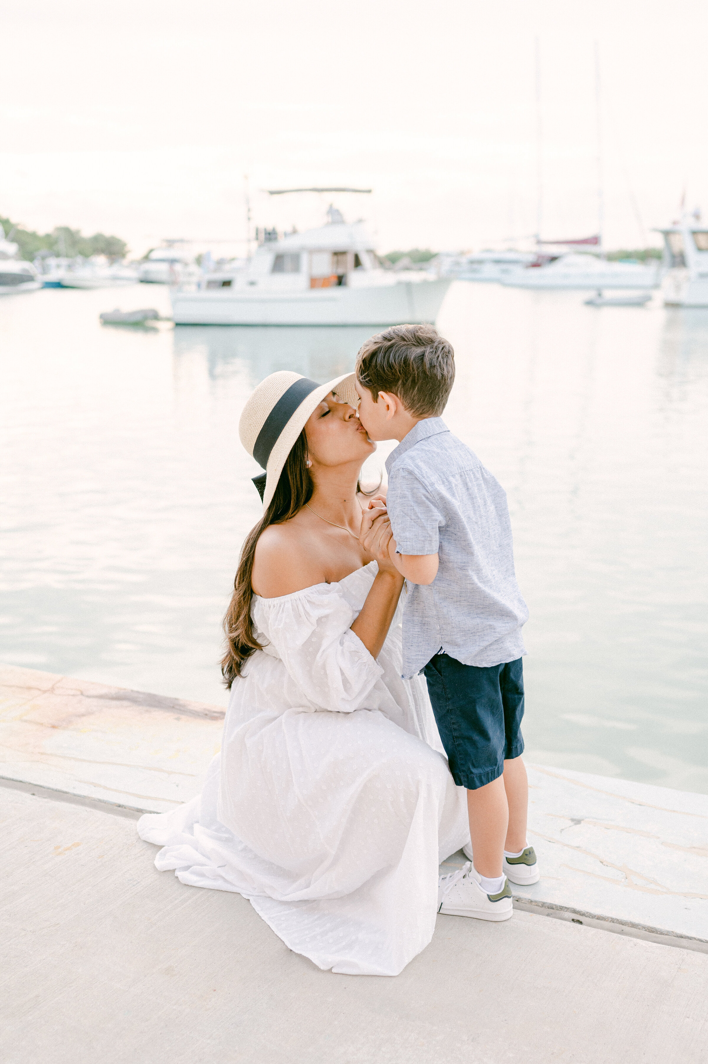 Mom kissing her little boy with boats in the background
