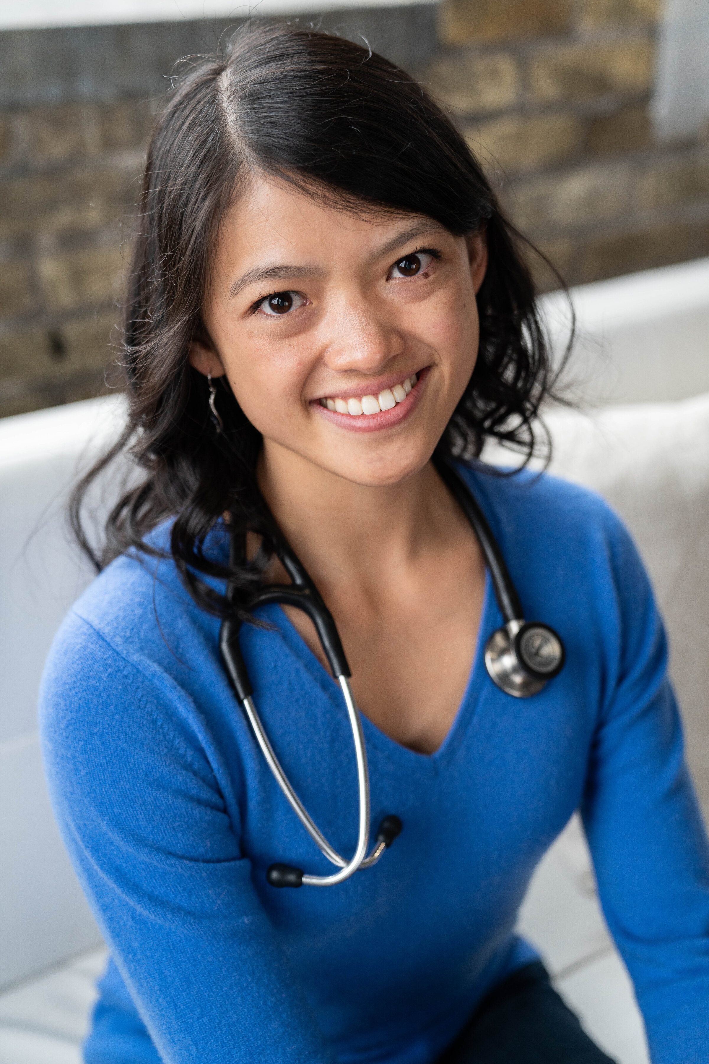 Veterinarian wearing a stethoscope around her neck smiles at the camera during her headshot photo shoot.