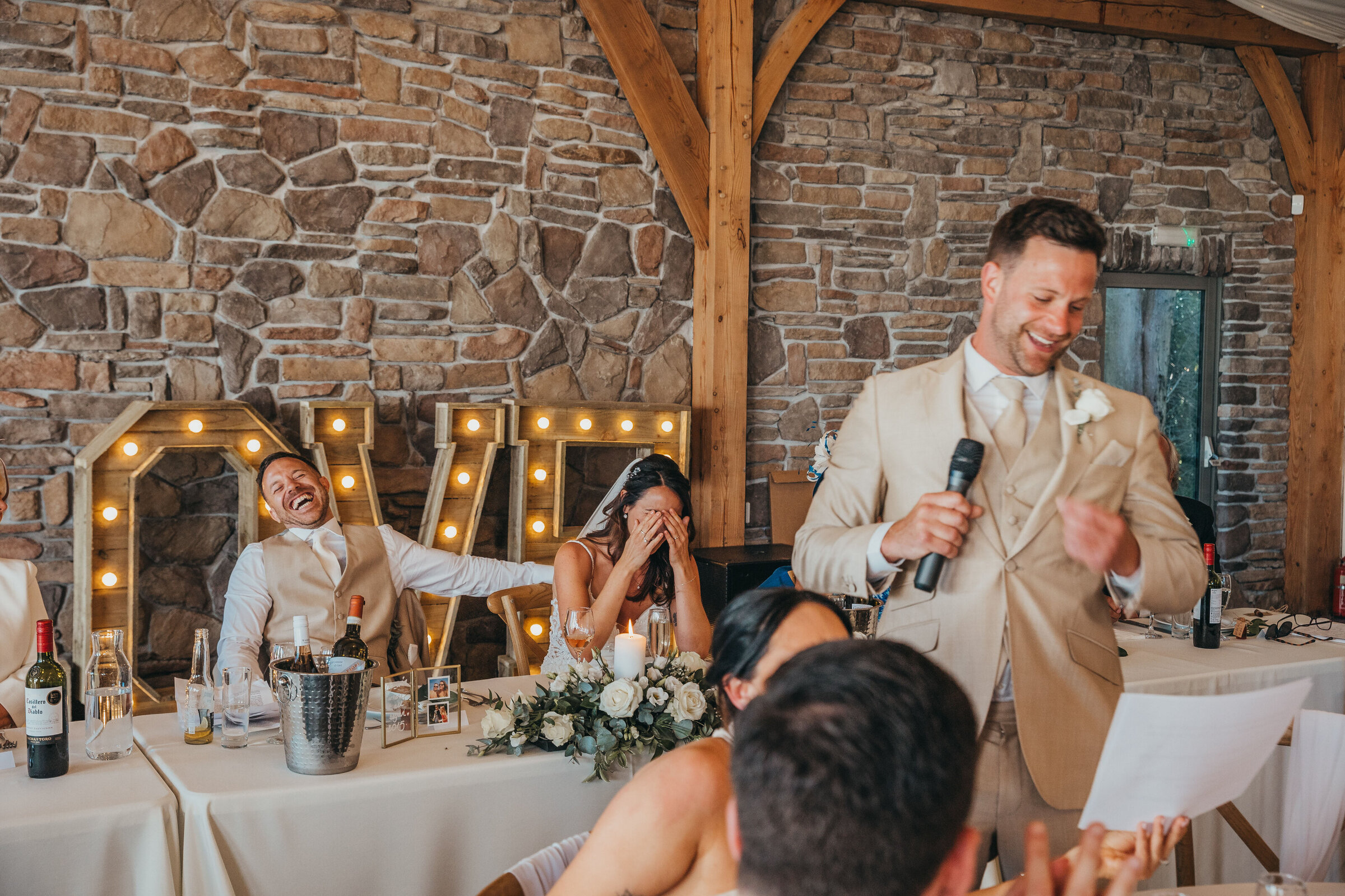 best man giving speech whilst guests laugh