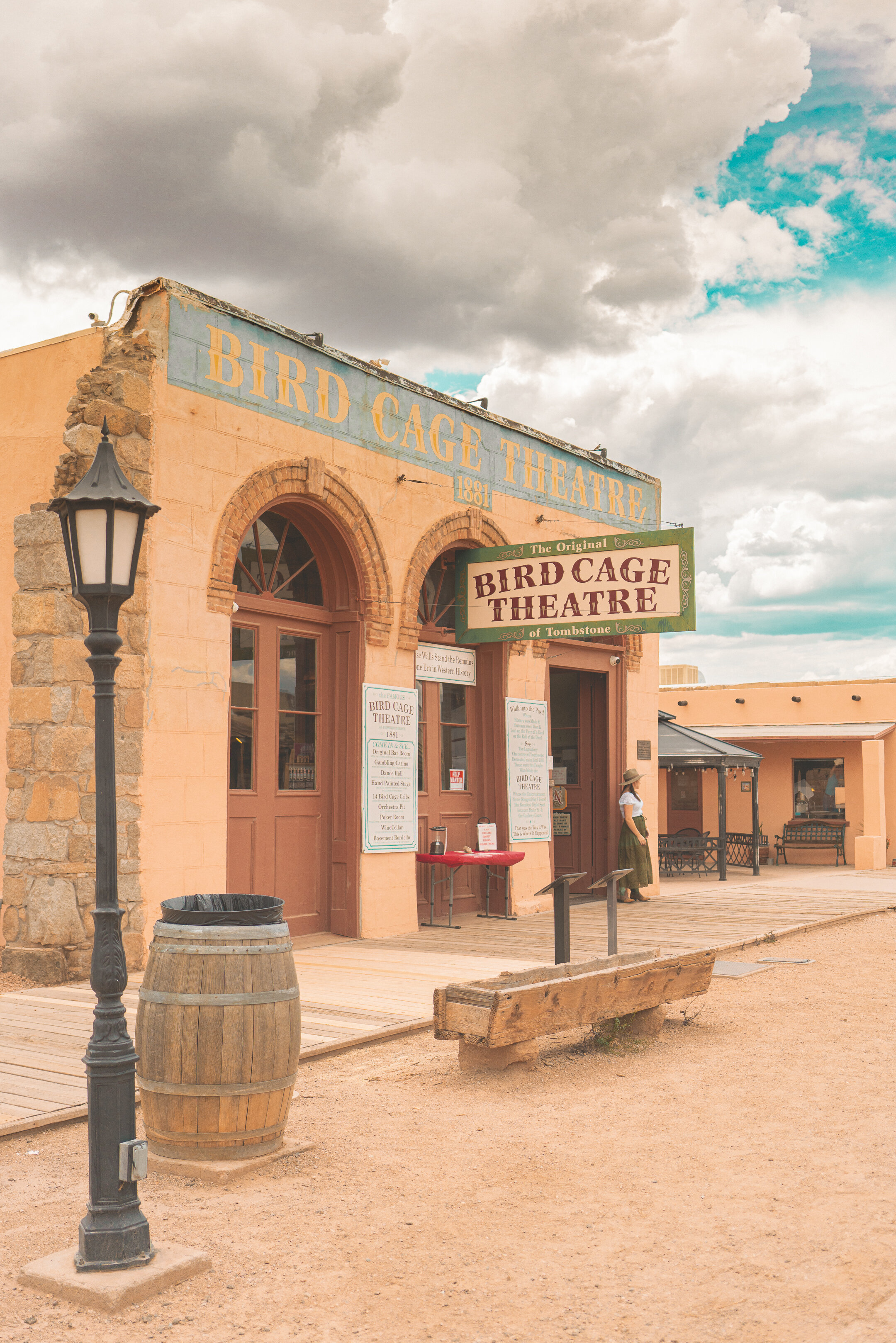 A peach-colored building with a sign reading 'Bird Cage Theatre' and a streetlamp in front.