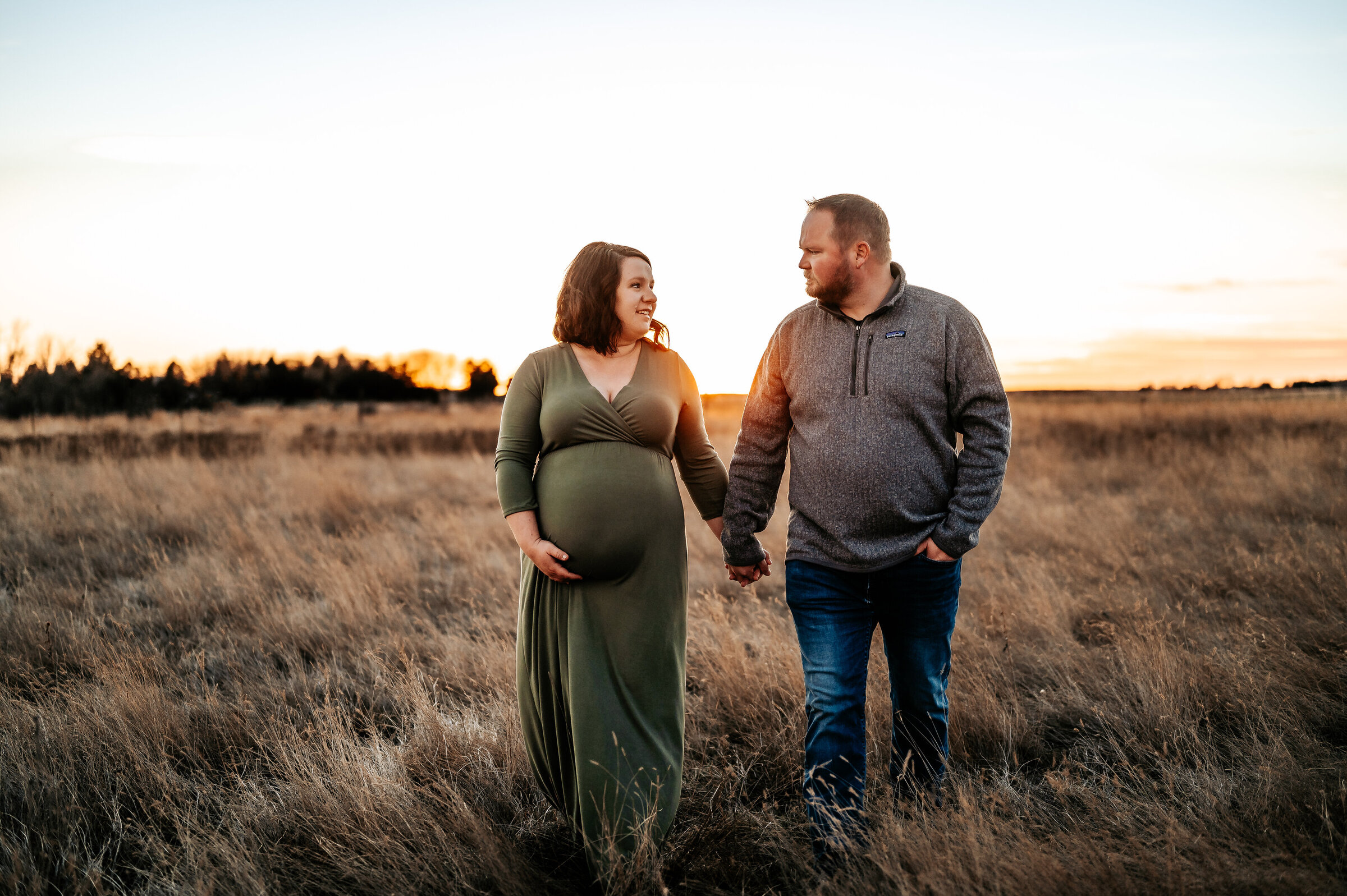 Man and woman look at each other while walking in maternity photos