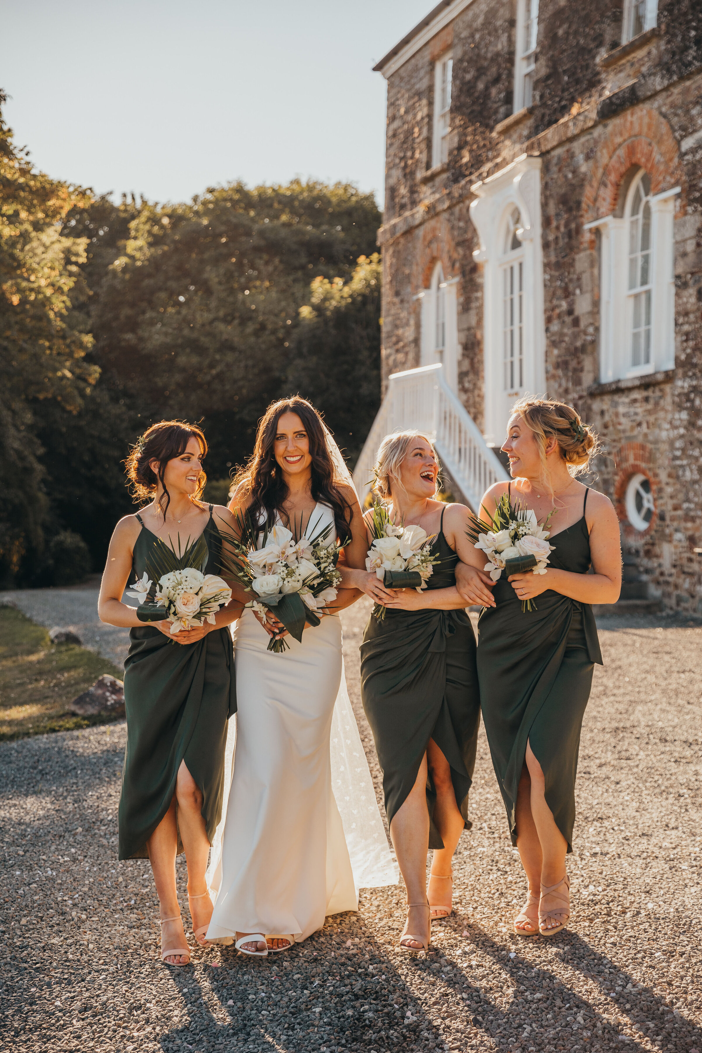 Bride and bridesmaids laughing with eachother during golden hour