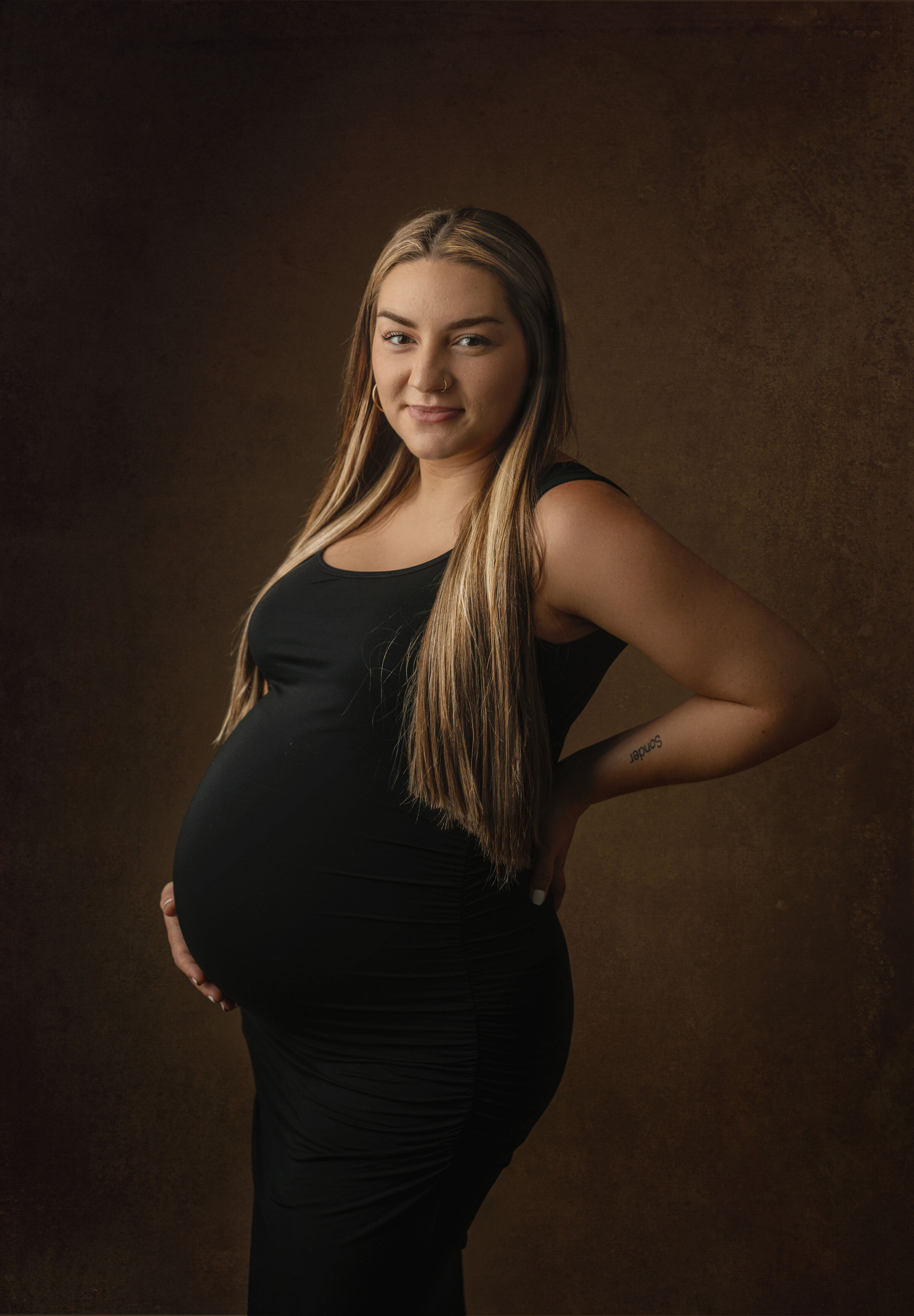 Pregnant women in bucyrus ohio studio, with  one hand on belly and one hand on her back