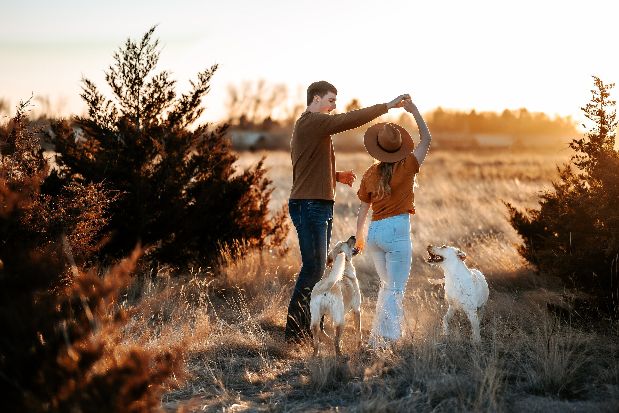 woman and man get engagement photos done with their dogs while man twirls woman