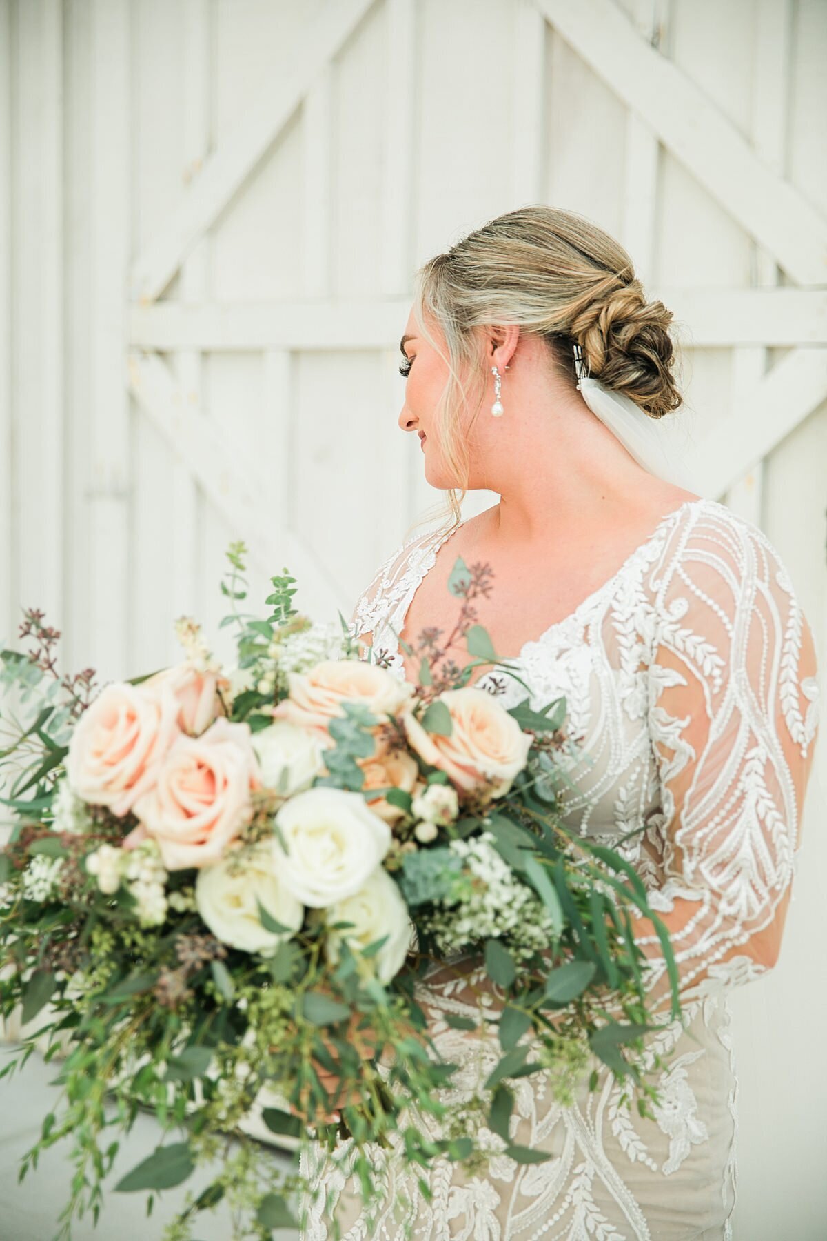 Bride holding large bouquet filled with greenery and roses