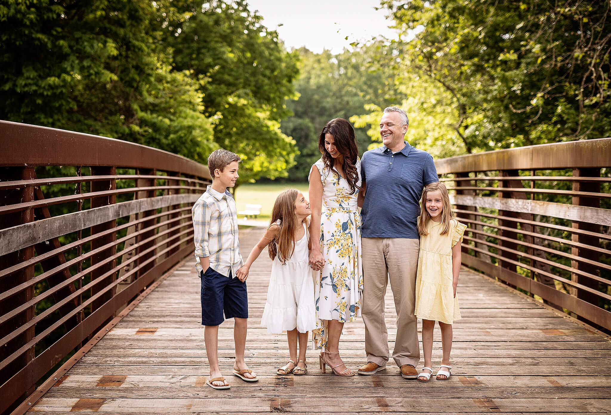 Mom and dad with three children standing on bridge at stepping stones park in Upper Sandusky Ohio