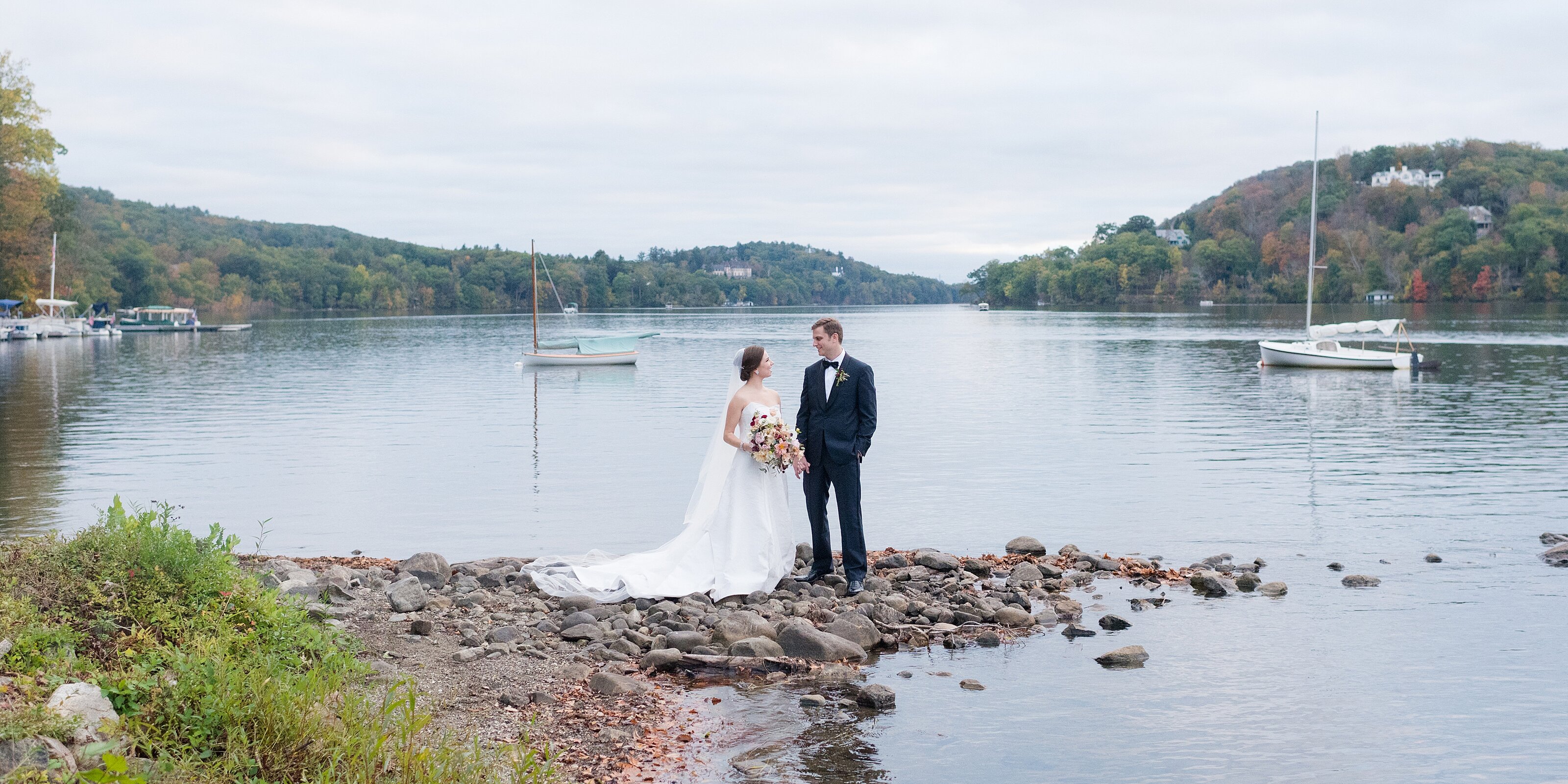 1_bride-and-groom-stand-on-small-rock-jetty-overlooking-the water