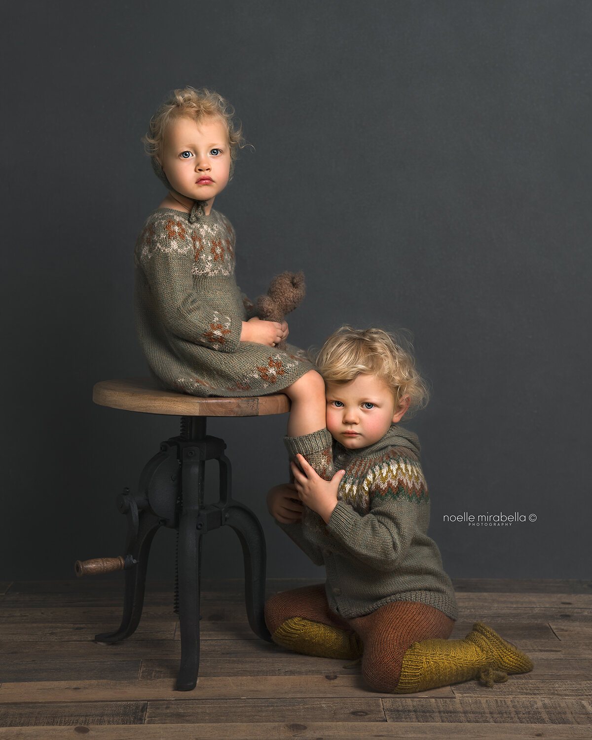 Two blonde, curly haired children in knits.