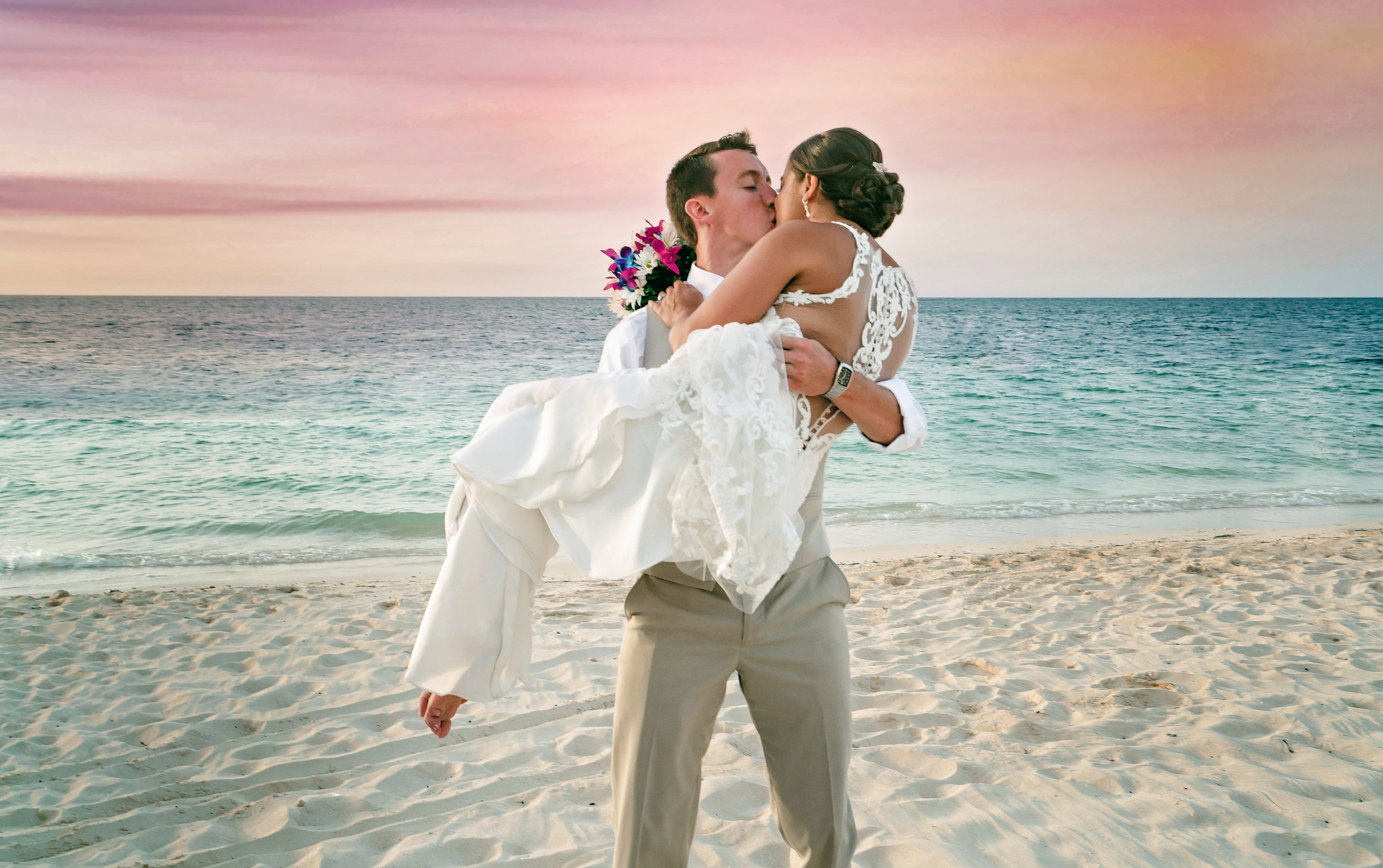groom picking up bride while kissing on the beach in jamaica