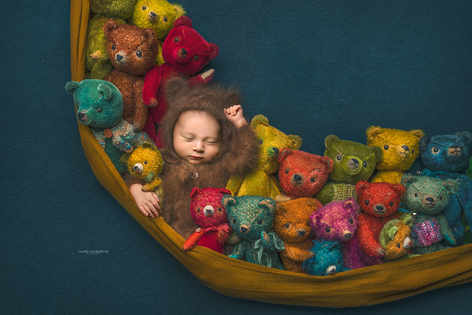 Newborn baby in teddy bear hammock full of multi-colour bears.