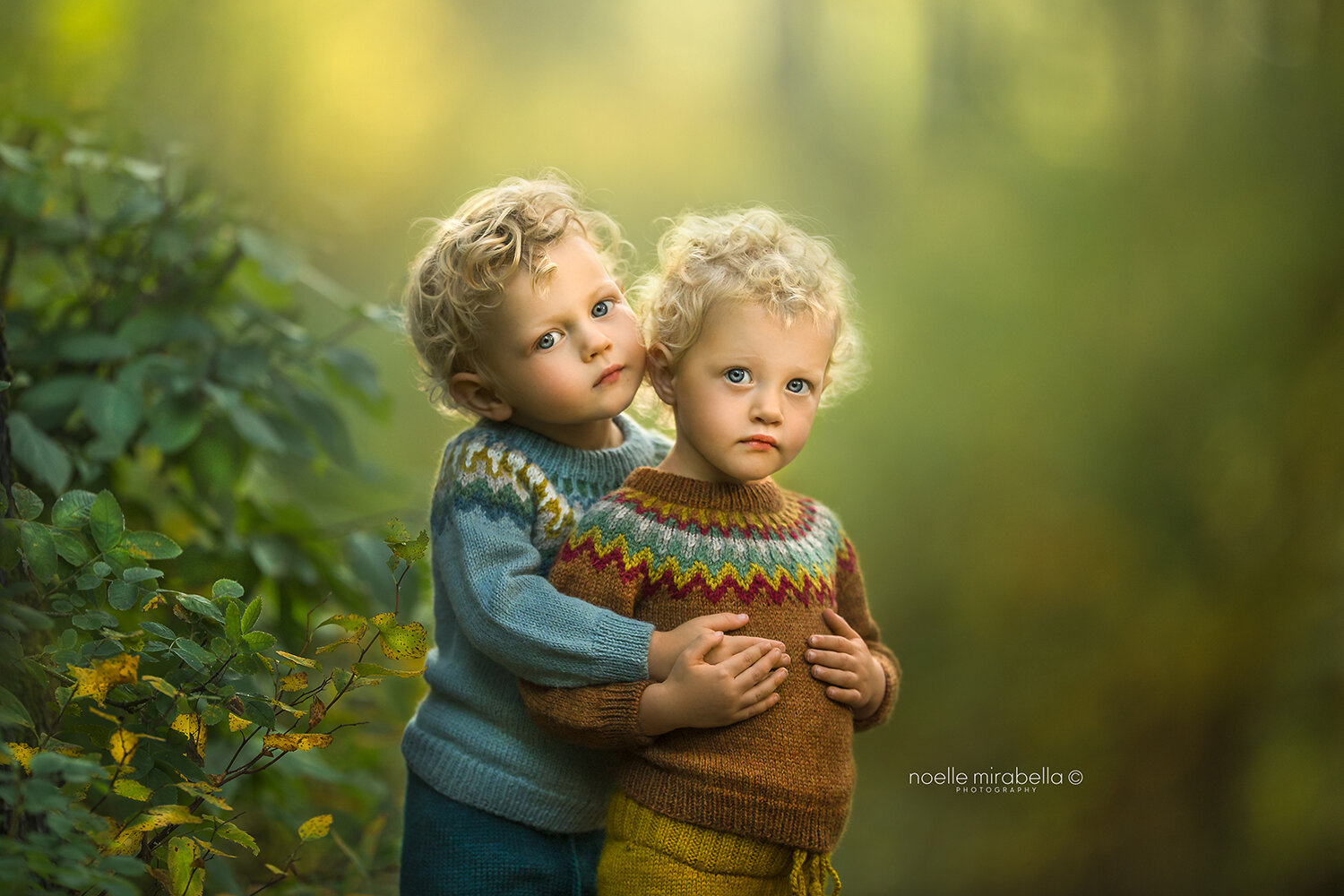 Two blond children hugging in a forest