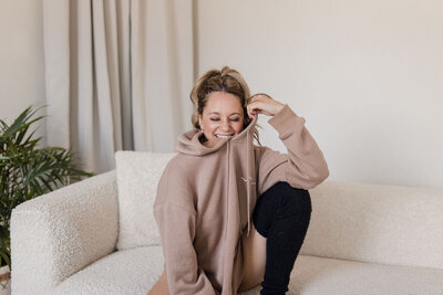 Martina Biljan, copywriter and creative brand strategist  smiling with eyes closed wearing pink hoodie