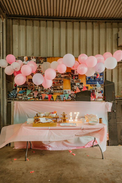 Styled pink balloon garland and dessert table setup for a 17th birthday celebration.