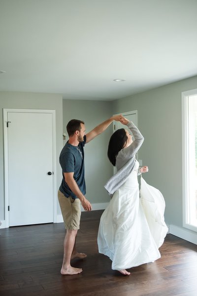 Bride wearing her wedding dress and dancing with her husband inside their home on their first anniversary