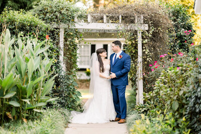 Bride and groom look at each other under a flower covered arbor at thompson house and gardens, monroe, Georgia