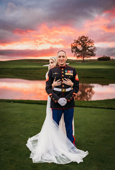 Wedding photography on golf course of bride standing behind husband in military outfit