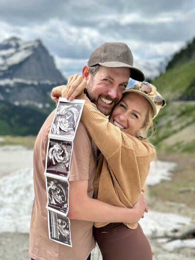 Excited couple hugging as they hold their ultrasound photos