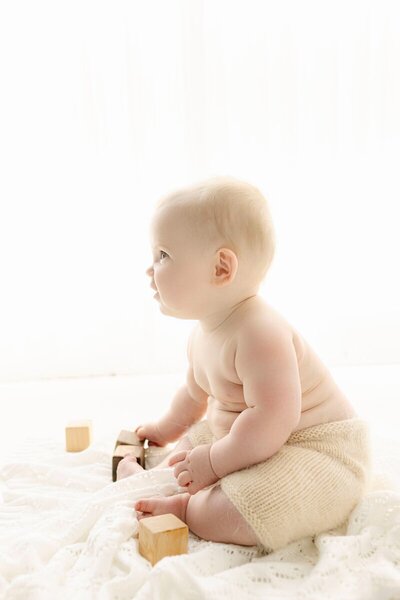 Baby sitting and playing with wooden blocks, taken by baby photographer nj