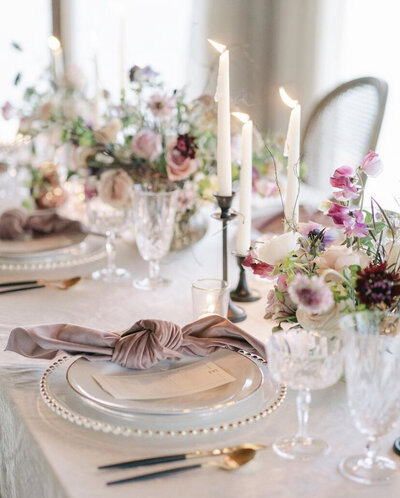 Blush and cream reception table with place settings and fresh floral centerpieces