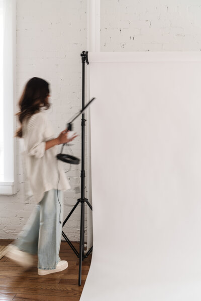 Blurred photo of a woman setting up a ring light