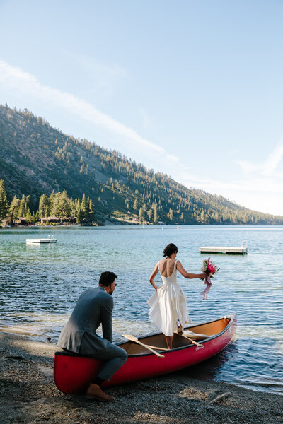 Bride and groom jump in a red canoe for their wedding ceremony recessional at Stanford Sierra Camp in Lake Tahoe