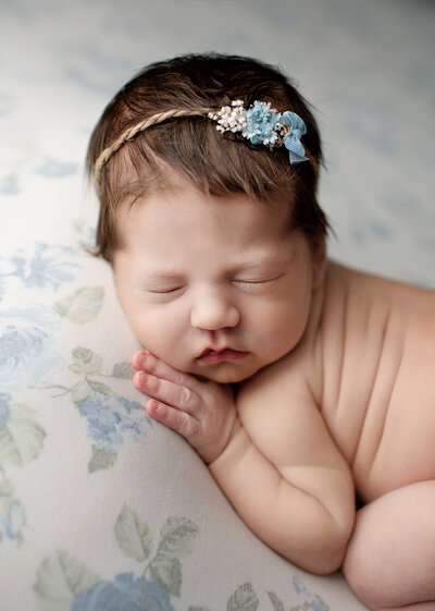 baby girl posed on blue floral backdrop